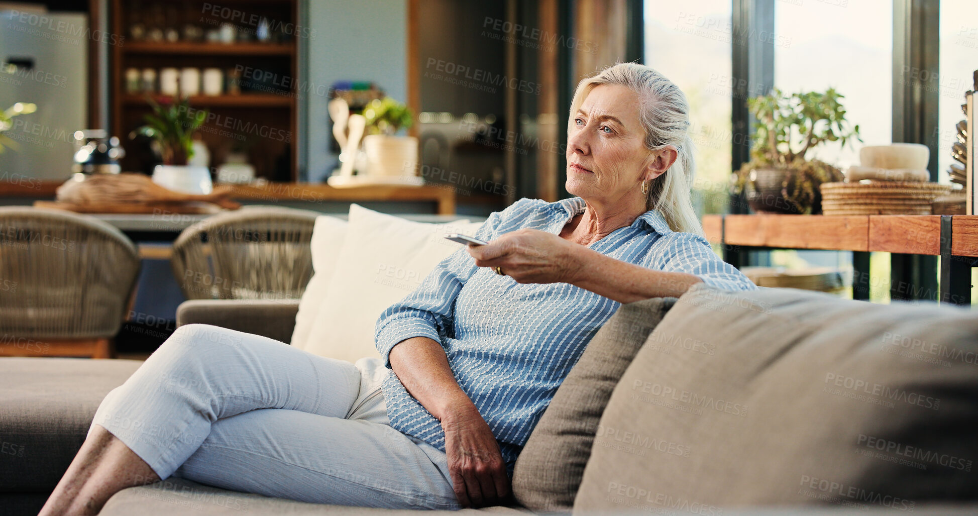 Buy stock photo Senior woman, watching tv and remote on couch, search and click for movie choice in retirement at house. Elderly person, television show and relax on sofa with streaming, film or subscription in home