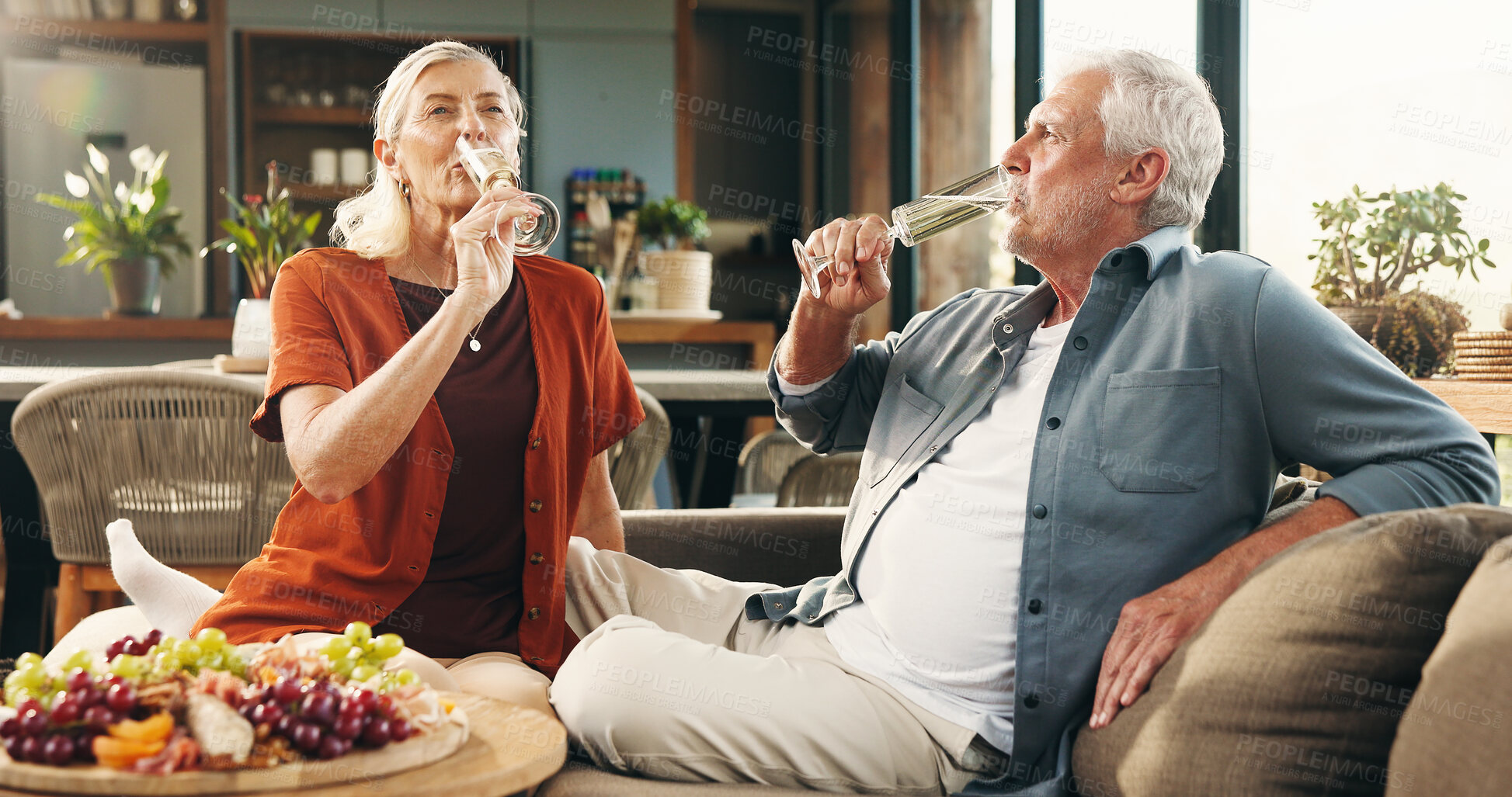 Buy stock photo Senior couple, champagne and location with drink for anniversary celebration or date in home. Elderly, man and woman with alcohol or charcuterie on sofa for valentines day or relationship in house