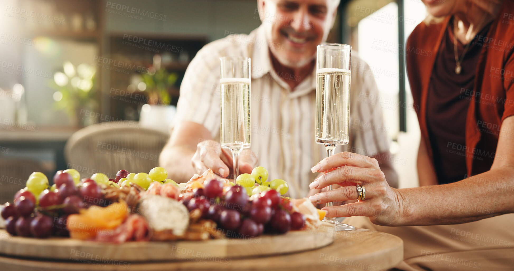 Buy stock photo Senior couple, hands and champagne with charcuterie board of fruit for anniversary or date in home. Elderly, man and woman with alcohol or organic food for valentines day or romance together in house