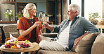 Elderly, happy couple and cheers with champagne for anniversary celebration or date in home. Senior, man and woman with alcohol, fruit or charcuterie board for valentines day or romance in house