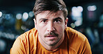 Portrait, tired and man in gym for fitness break, wellness and recovery from intense exercise. Serious, fatigue and person in workout club for rest, health and breathing for challenge with bokeh