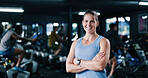Portrait, personal trainer and woman with arms crossed, gym and confident for fitness in spin class. Happy, instructor and people with bikes for health benefits, wellness and exercise on equipment