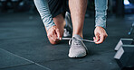 Person, hands and tying with shoes for fitness, workout preparation or indoor training in gym. Closeup, active or runner getting ready with sneakers, laces or dumbbells for exercise in health club