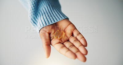 Buy stock photo Hand, pills and person with medication in studio for health, wellness or sickness recovery. Pharmaceutical, immune booster and model with capsules for vitamins, tablets or medicine by gray background