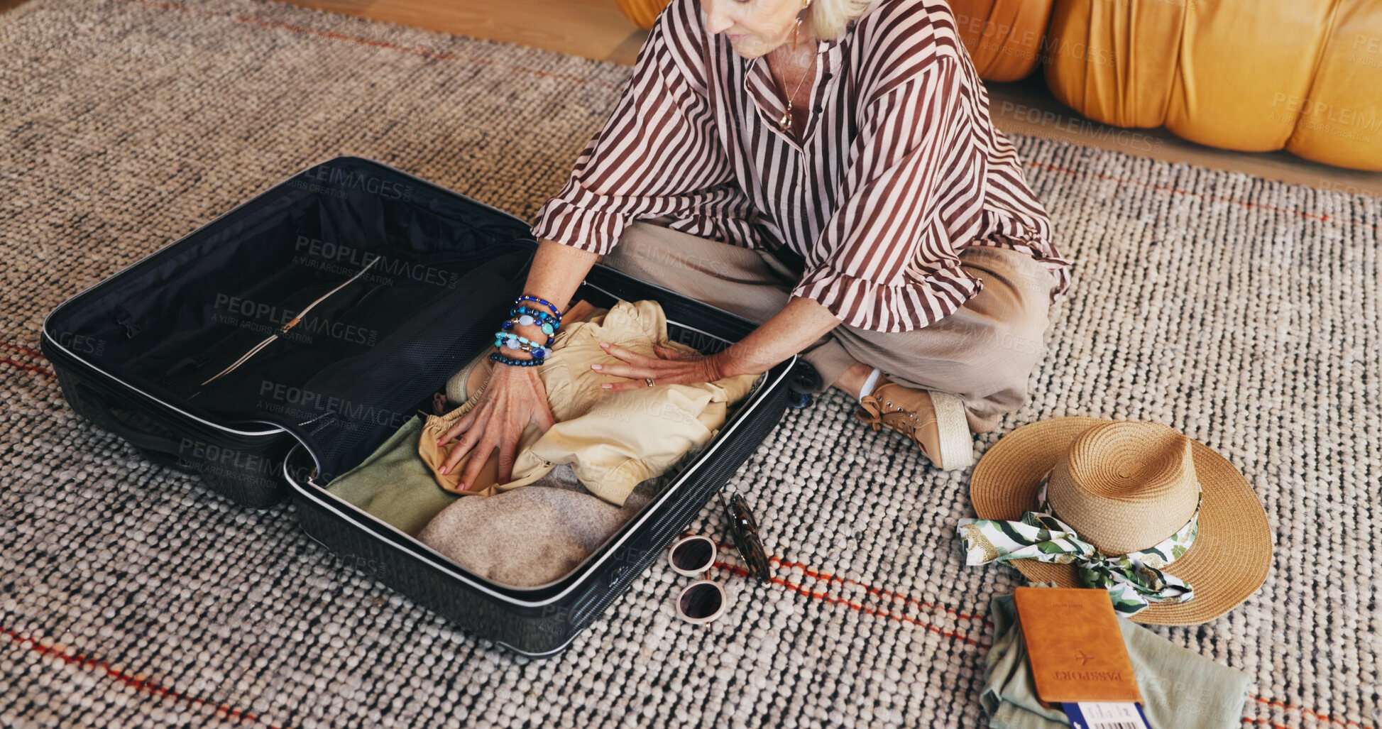 Buy stock photo Mature woman, travel and packing with suitcase in home for holiday, vacation or getaway. Hands, female person or traveler with clothing, luggage or passport ticket for preparation or flight booking