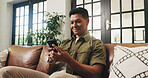 Smile, man and relax with phone at sofa for communication, social media and browsing website. Happy, male person and mobile for reading chat on app, download games and message notification at house