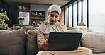 Muslim woman, laptop and reading on couch for learning, online Quran course or Arabic language studying. Education, pc and person with hijab in home for religious understanding, research or knowledge
