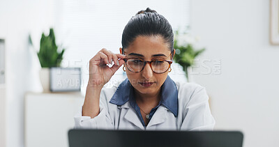 Buy stock photo Glasses, healthcare and laptop with doctor in office at hospital for online planning or research. Computer, medical and reading with Indian woman in clinic for administration, report or study