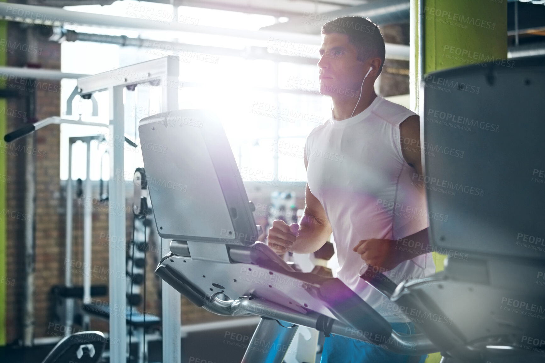 Buy stock photo Earphones, fitness and man running on treadmill for exercise, wellness and listening to audio in gym. Cardio machine, music and person training in health club for workout, challenge and flare