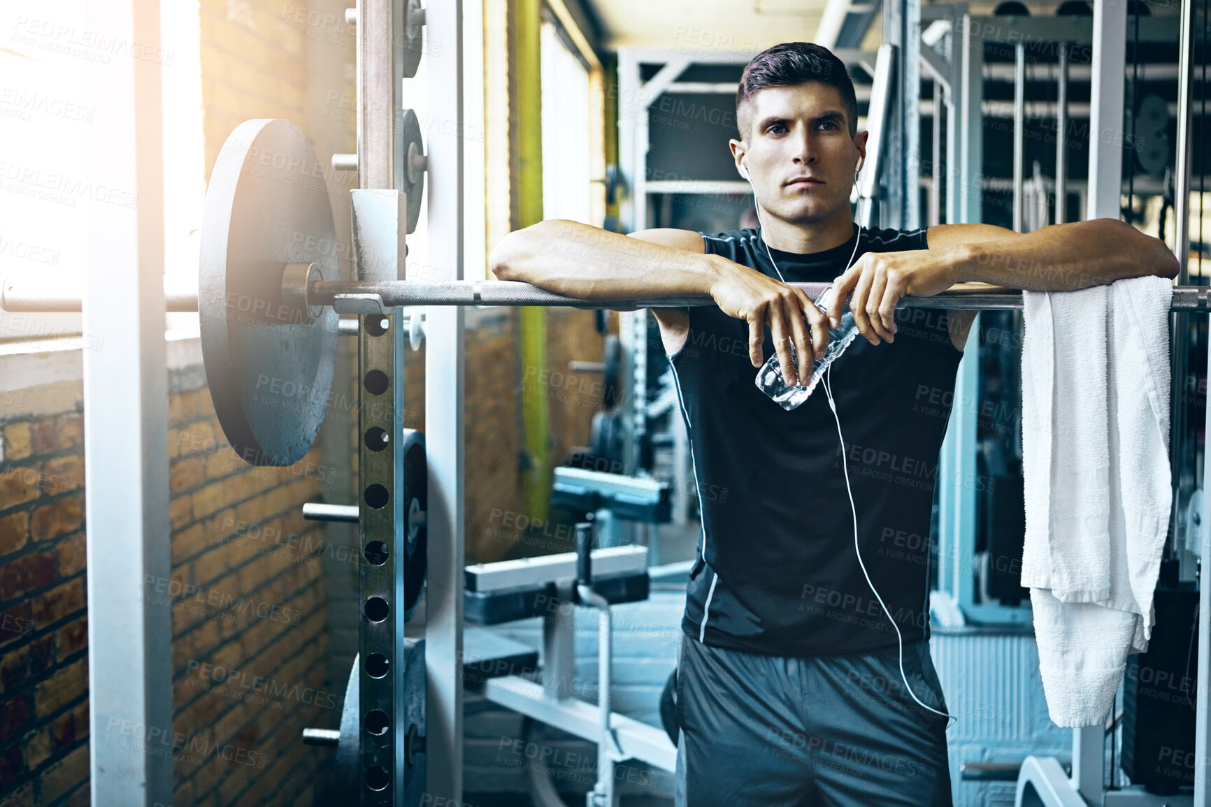 Buy stock photo Barbell, break and water with man in gym for strength training or workout routine. Earphones, hydration and weightlifting with bodybuilder in health club for challenge, physical improvement or rest