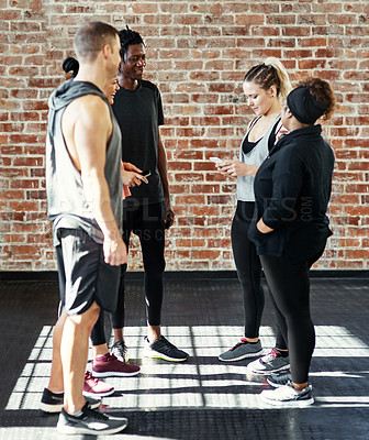 Buy stock photo Workout, group and talking with phone at gym for exercise break, track progress or wellness advice. Men, women and conversation with tech at health club for tracking fitness, share tips and support