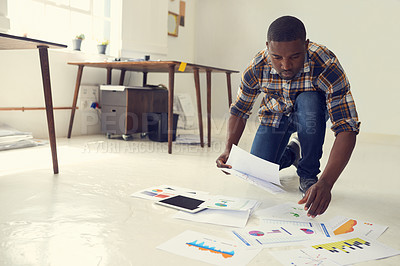 Buy stock photo Paperwork, reading or black man on floor in creative agency, research or data analysis for consumer trends. Brand sales, startup or marketer with online engagement info, chart and graphs for planning