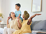Lesbian couple, gay family and boy child on a sofa with piggyback, game and fun in their home together. Love, lgbt and women mother in a living room with kid and shoulder, hug and playing in a house