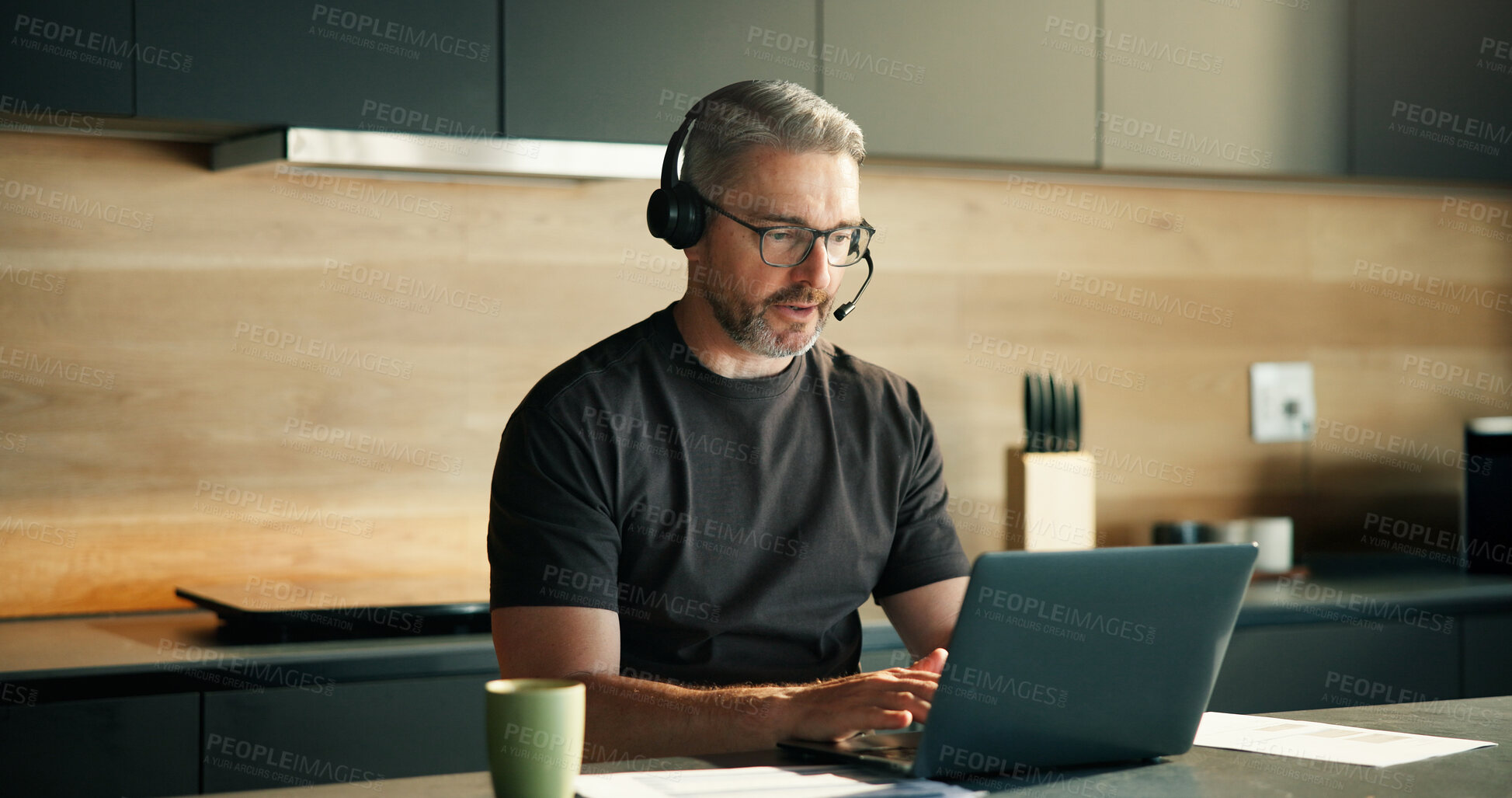 Buy stock photo Headset, laptop and remote work with man in kitchen of home for customer service or support. Computer, consulting and typing with mature freelancer in apartment for contact us, crm or problem solving