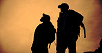 Mountain, sunset and silhouette of men with hiking, travel and backpacking with view and below. Shadow, eco tourism and outdoor with evening, nature and fitness or exercise for wellness with friends