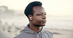 Black man, thinking and earphones at beach for fitness, smile or streaming service for wellness. African person, runner and listen to music with space, sea promenade and subscription for exercise