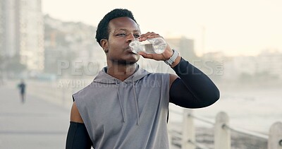 Buy stock photo Man, fitness and drinking water at beach on promenade, break and outdoor with hydration for wellness. Person, runner and bottle with space, electrolytes and rest with exercise on boardwalk by ocean