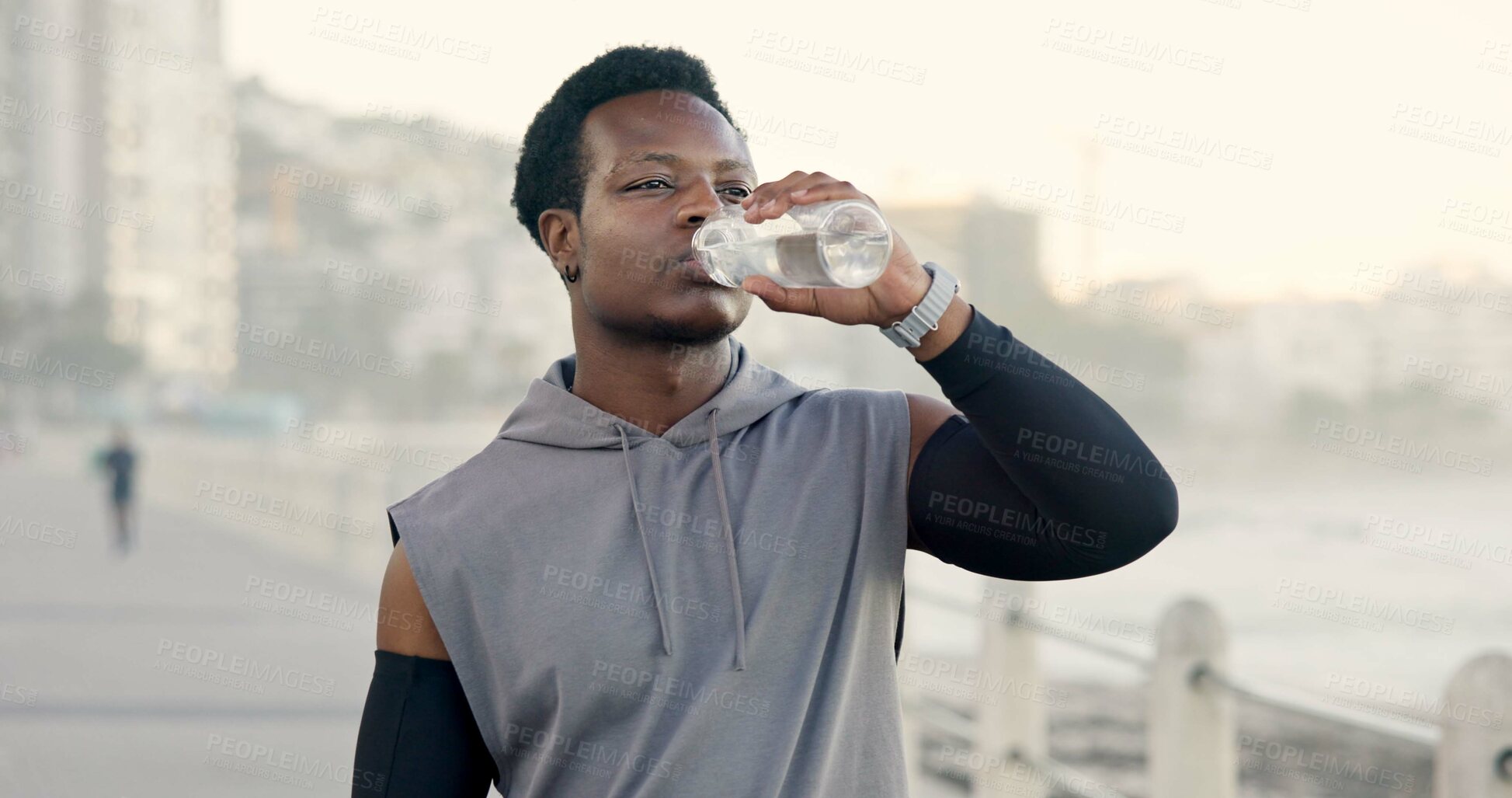 Buy stock photo Man, fitness and drinking water at beach on promenade, break and outdoor with hydration for wellness. Person, runner and bottle with space, electrolytes and rest with exercise on boardwalk by ocean