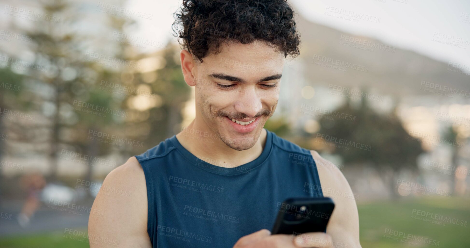 Buy stock photo Man, phone and texting with fitness in city at park with smile, break and scroll on application. Person, runner and happy with smartphone, check notification and outdoor for exercise in urban town