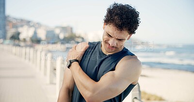 Buy stock photo Man, shoulder pain and fitness with injury on beach promenade for break with sore muscle in summer. Person, runner and fatigue with joint strain, exercise and rest on seaside boardwalk in urban town