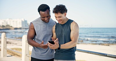 Buy stock photo Beach, athlete and men with smartphone, break and check exercise stats on website, happy and online. Ocean, runner and people with mobile for fitness progress, space or friends with tech in nature