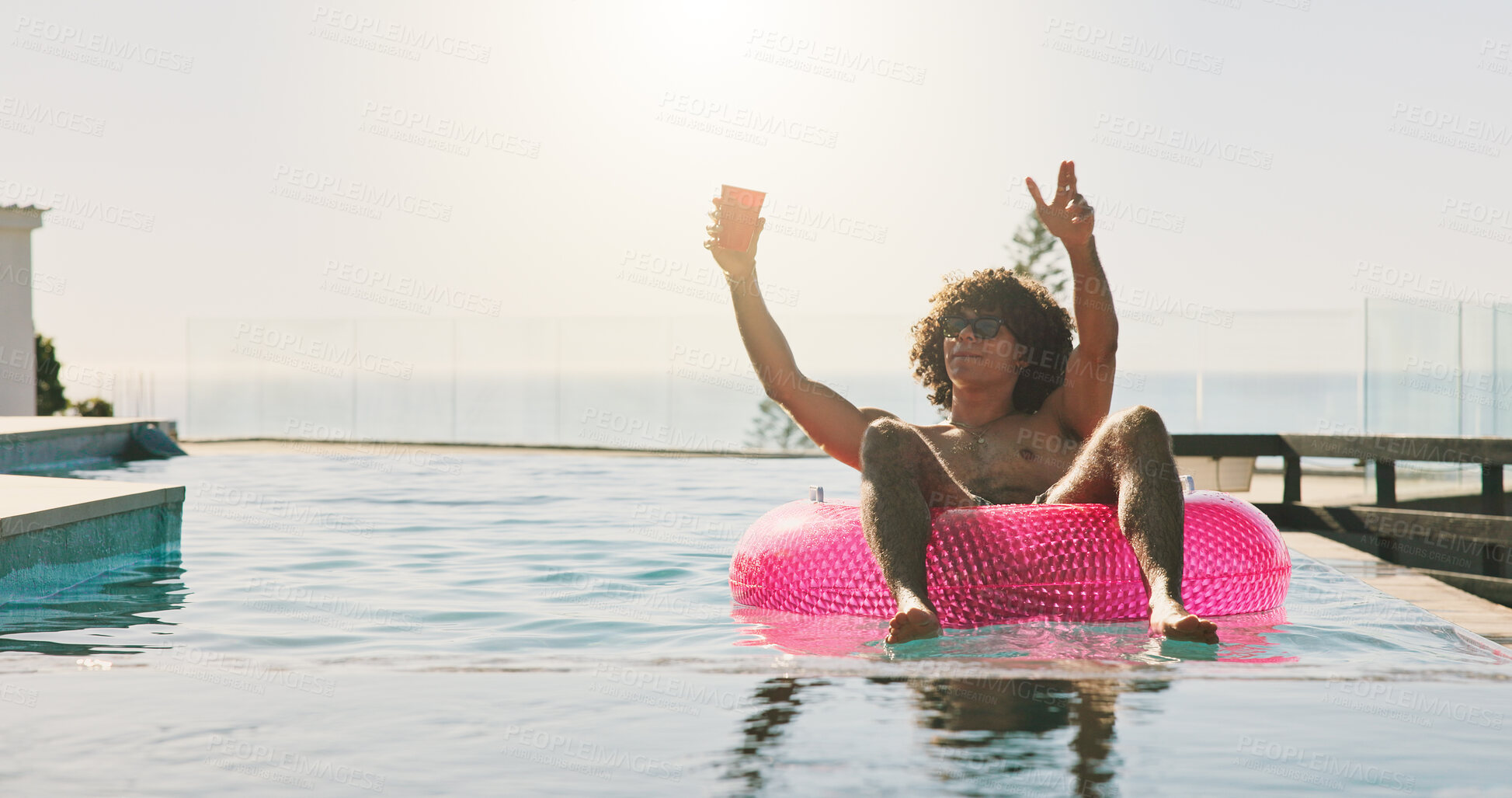 Buy stock photo Swimming pool, party and man with vacation, sunshine and relax with weekend break. Water, floating and person with happiness, summer holiday and flare with tropical escape,  inflatable and chilling