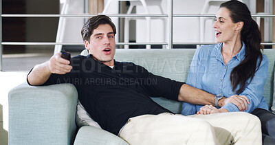 Buy stock photo Home, watching tv and couple on sofa, smile and bonding together for fun, playful and relax. Apartment, man and woman on couch, remote control and entertainment for hobby, competitive and happiness