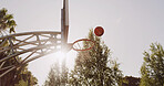 Basketball, rim and board in nature for sports, competition and training with ball in air for goal. Hoop, backboard and game with net for exercise, sky or sunshine with low angle of stanchion outdoor