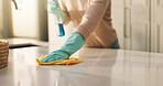 Person, hands and cleaning surface with detergent in kitchen for housekeeping or hygiene in home. Cleaner, wipe and counter with gloves, cloth or spray bottle for bacteria, germ or dirt removal