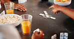 Hands, group and play dominoes in home with snacks, bonding and relax with challenge on break. People, friends and above with game, strategy and competition with drinks with reunion at apartment