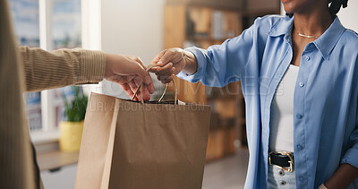 Buy stock photo Hands, paper bag and people in boutique, employee and discount deal with purchase. Business owner, consumer and customer in store, giving and retail for shopping spree, spending and buying products