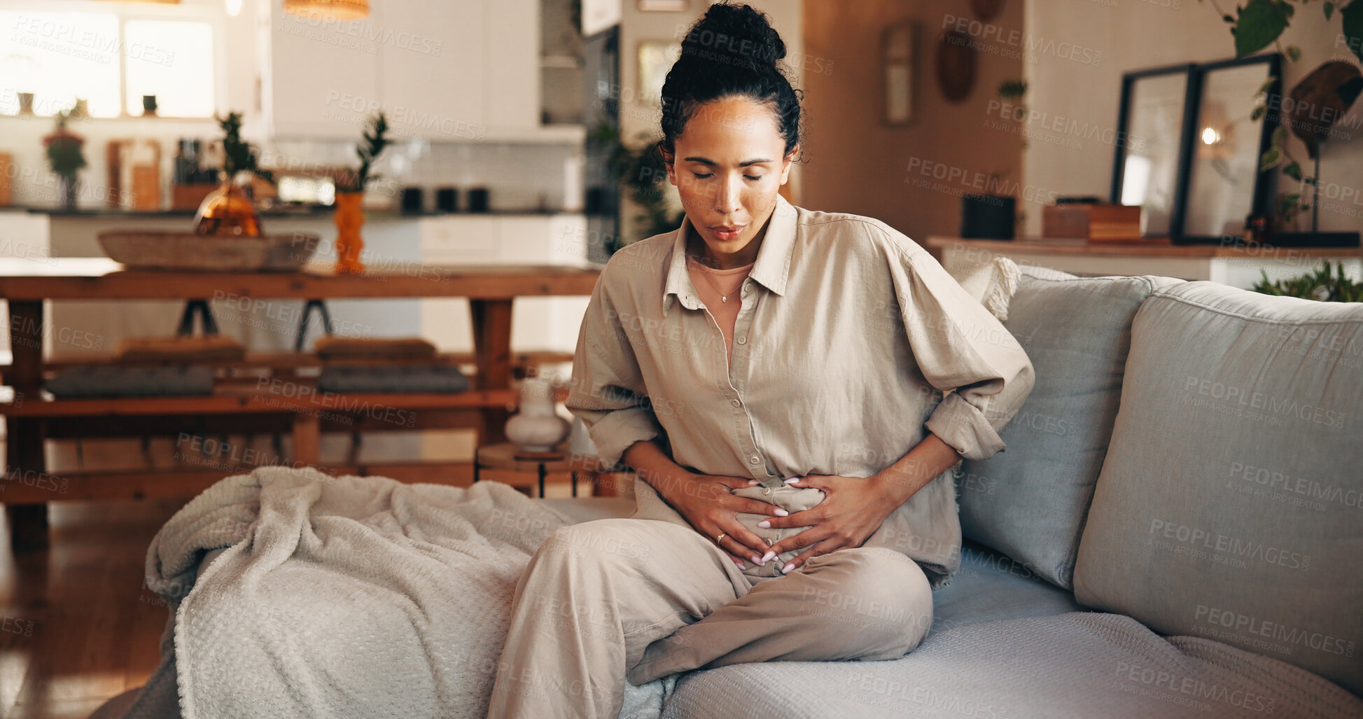 Buy stock photo Woman, stomach ache or period with pain on sofa for indigestion or menstruation cycle in home. Female person, discomfort or sore tummy bug with cramps or gastrointestinal reflux for virus or diarrhea