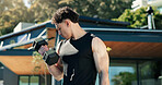 Bodybuilder, man and outdoor with dumbbells for fitness, muscle development and health. Morning, training and athlete person with weights for exercise by home for endurance, challenge and workout