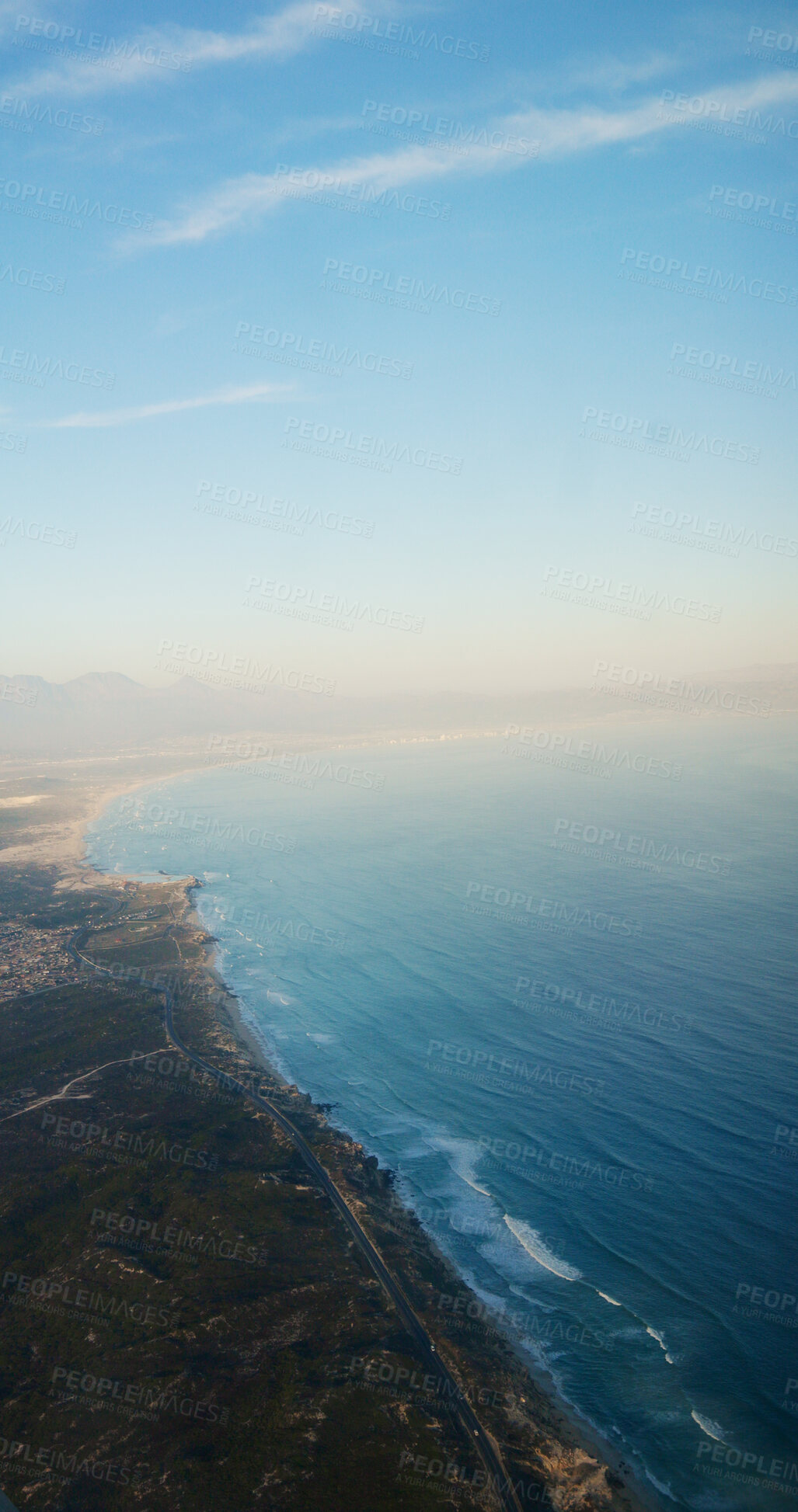 Buy stock photo Aerial view, seaside and coast with sky, mountains and cliff with space, outdoor and nature in summer. Ocean, shoreline and water with landscape, beach and above for hills with clouds on horizon