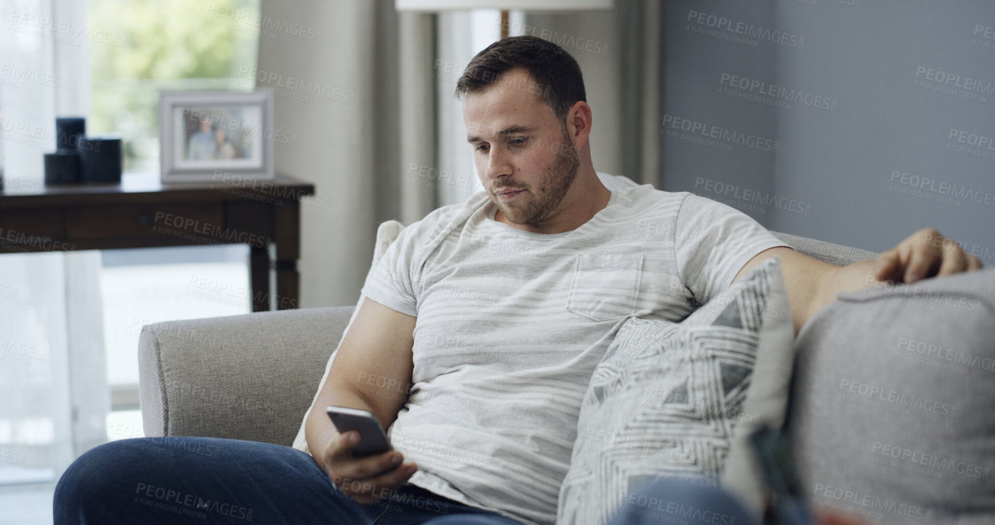 Buy stock photo Man, relax and reading on couch with phone, text message notification and website for news on weekend. Person, chill and scroll in home with tech, social media post and mobile app for online article.