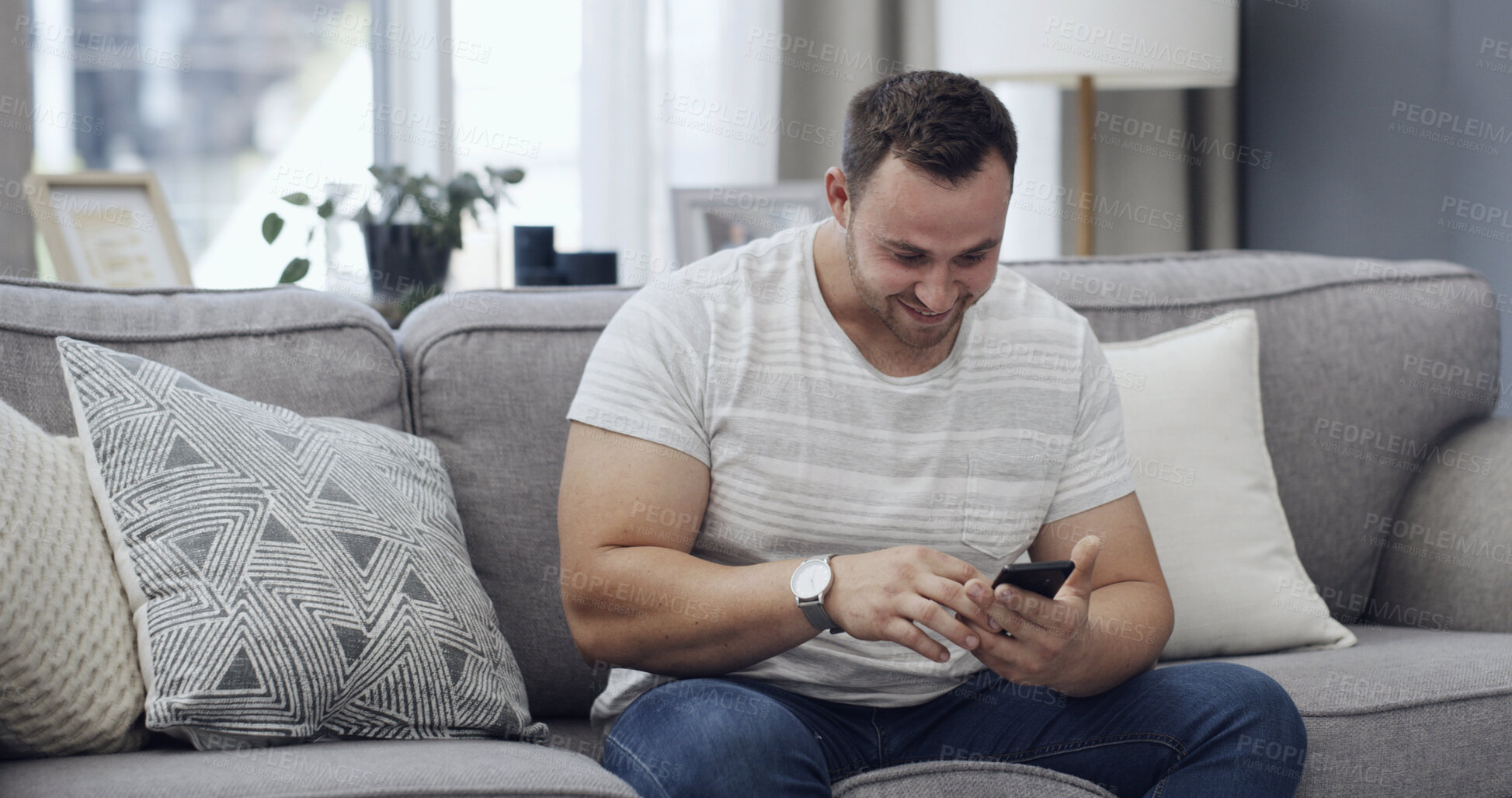 Buy stock photo Man, smile and scroll on sofa with phone, text message notification and download app for online dating. Happy, person relax and reading in home with tech, social media post and digital communication.
