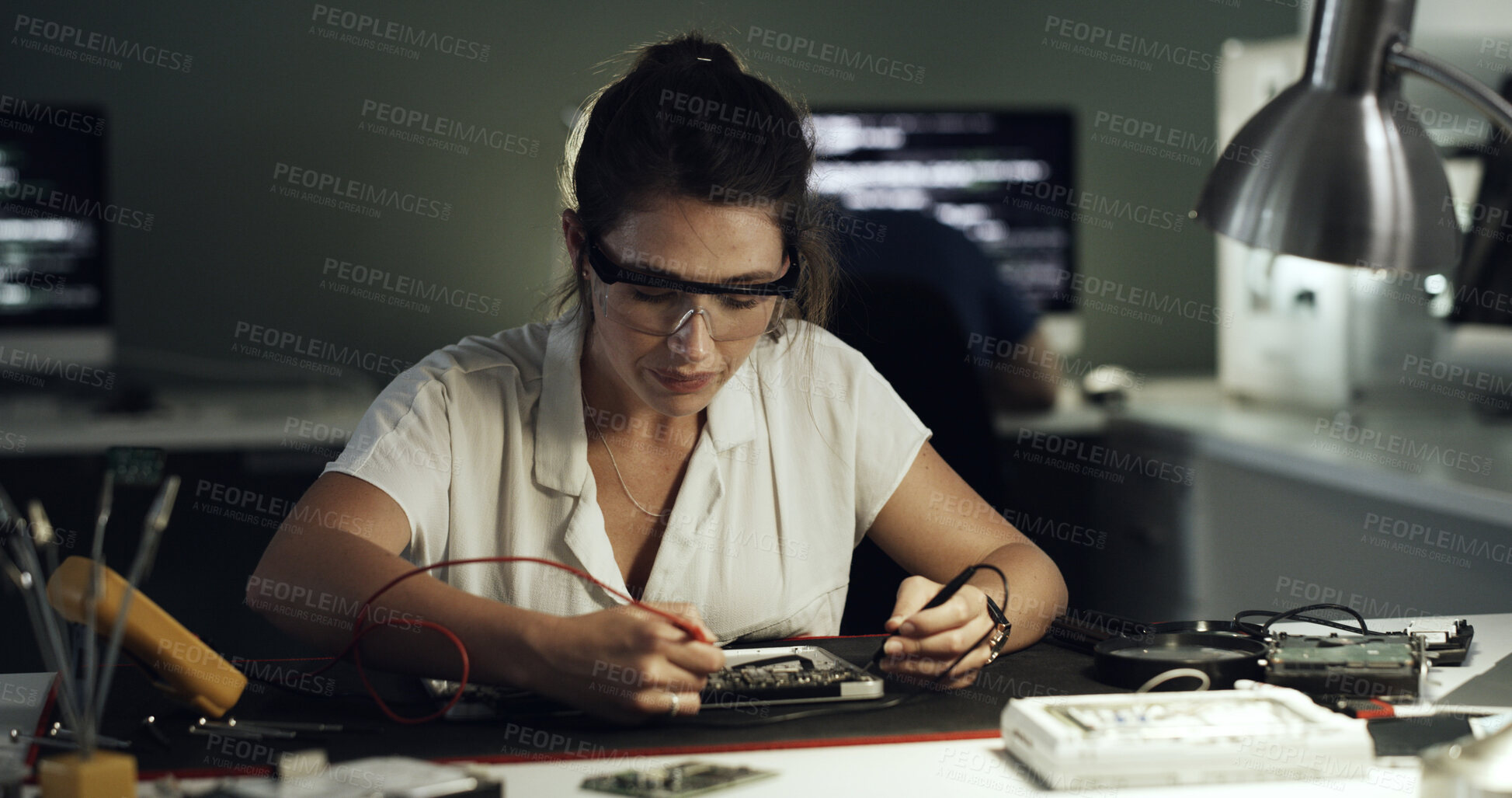 Buy stock photo Soldering, woman or circuit repair in office for hardware diagnostics, PCB maintenance or electronics. Night, technician and multimeter probe on motherboard for continuity, broken traces and safety