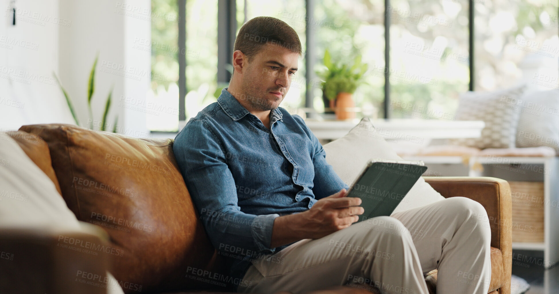 Buy stock photo Relax, man or reading tablet on sofa for social media post, streaming subscription or weekend break. Serious, person and tech in home for watching online videos, app download and email notification