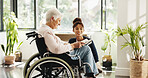 Old woman, nurse and reading book with wheelchair in house for smile, support or recovery for injury. People, caregiver and elderly patient with disability, rehabilitation or literature in retirement