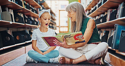 Buy stock photo Grandmother, reading book and girl in library, surprise and bonding together for child development. Senior woman, kid or family on floor, wow or support for education, literacy, hobby or storytelling