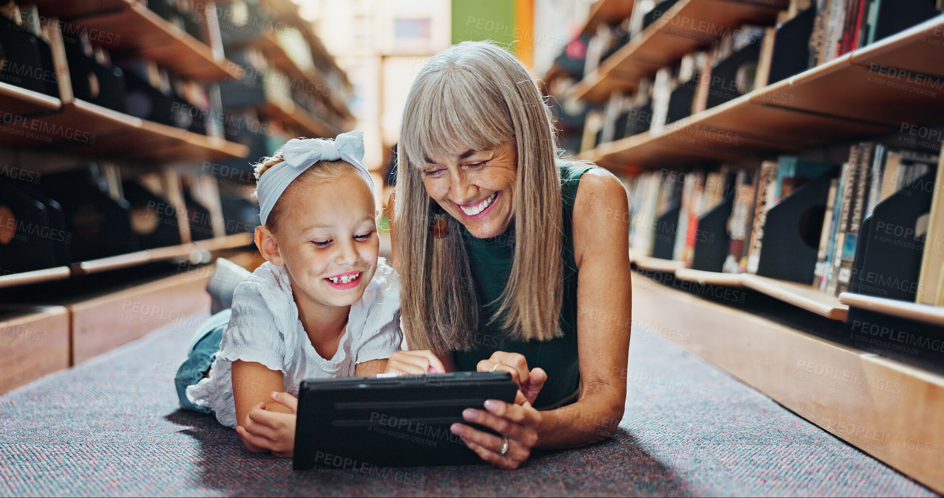 Buy stock photo Child, tablet and grandmother in library with ebook, bonding and reading literature for development. Happy, grandparent and girl grandchild with tech for kids storytelling app, learning or knowledge.