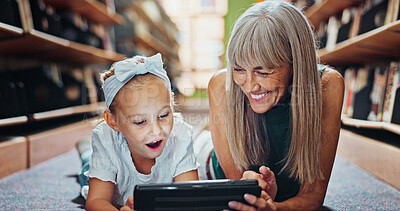 Buy stock photo Girl, tablet and grandmother in library with ebook, bonding or shocking literature for development. Happy, senior woman and grandchild reading with surprise for storytelling kids app, tech or fiction