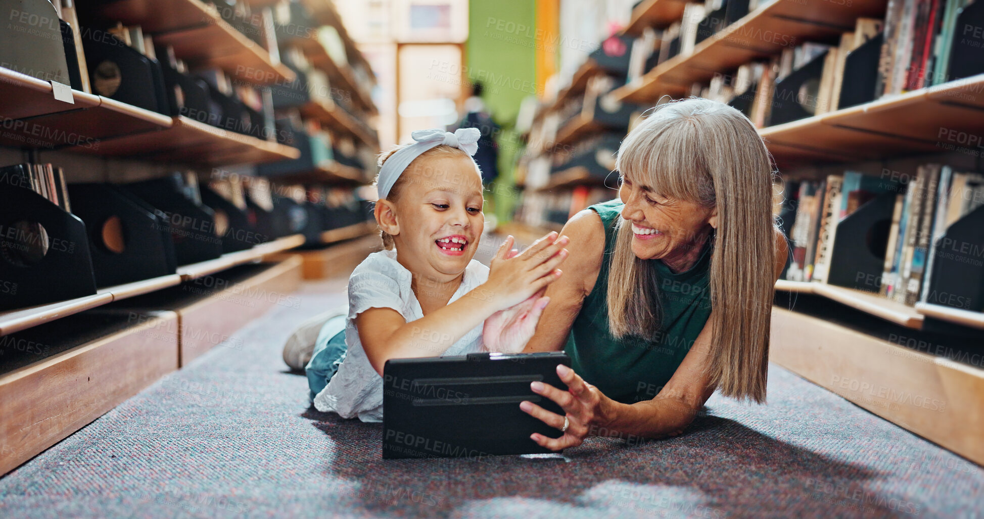 Buy stock photo High five, library and tablet with student and teacher on floor together for learning or reading. Celebration, education and success with woman teaching excited girl child in school for growth