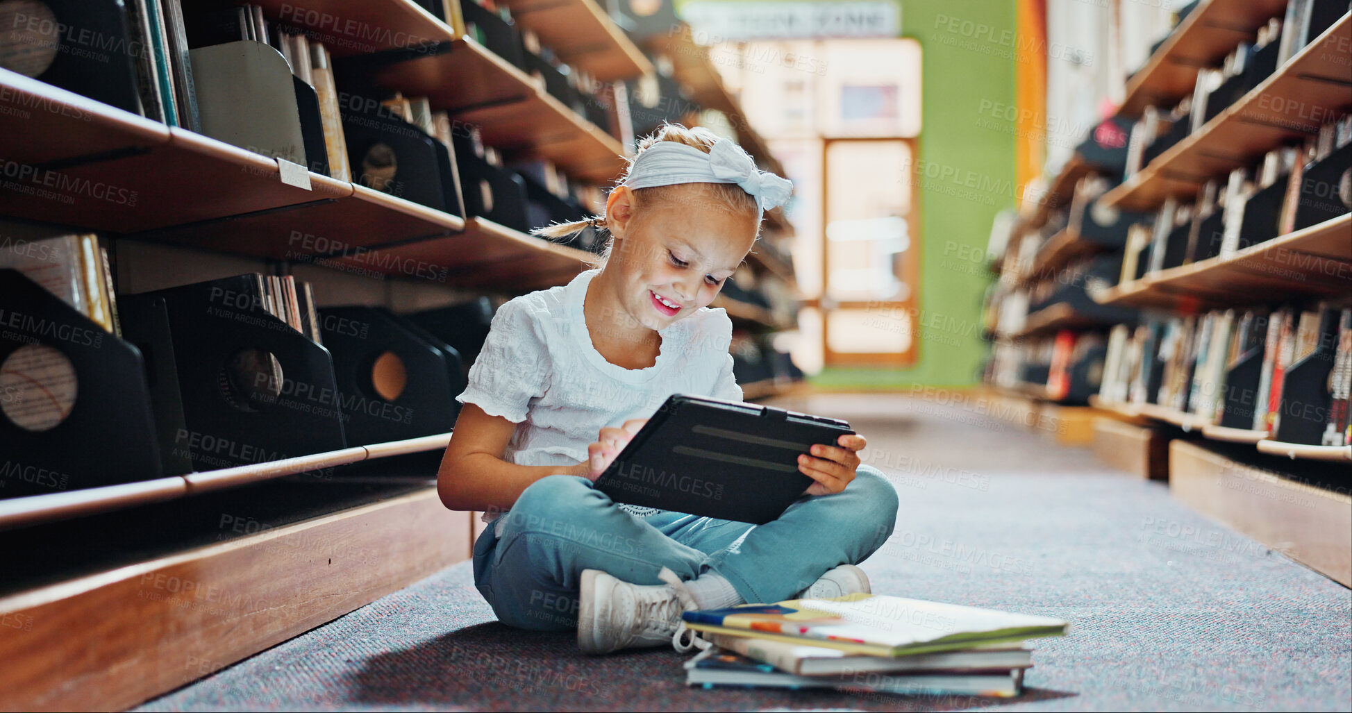 Buy stock photo Girl, kid and reading in library with tablet, ebook website and online literature for development. Child, smile and scroll at school with tech, storytelling app and education for knowledge growth.