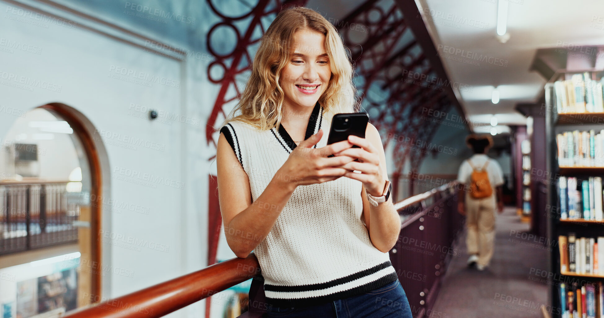 Buy stock photo Woman, university student and texting with phone at library for education, smile or contact at campus. Girl, smartphone and happy for web chat, mobile app and social media on study break at college