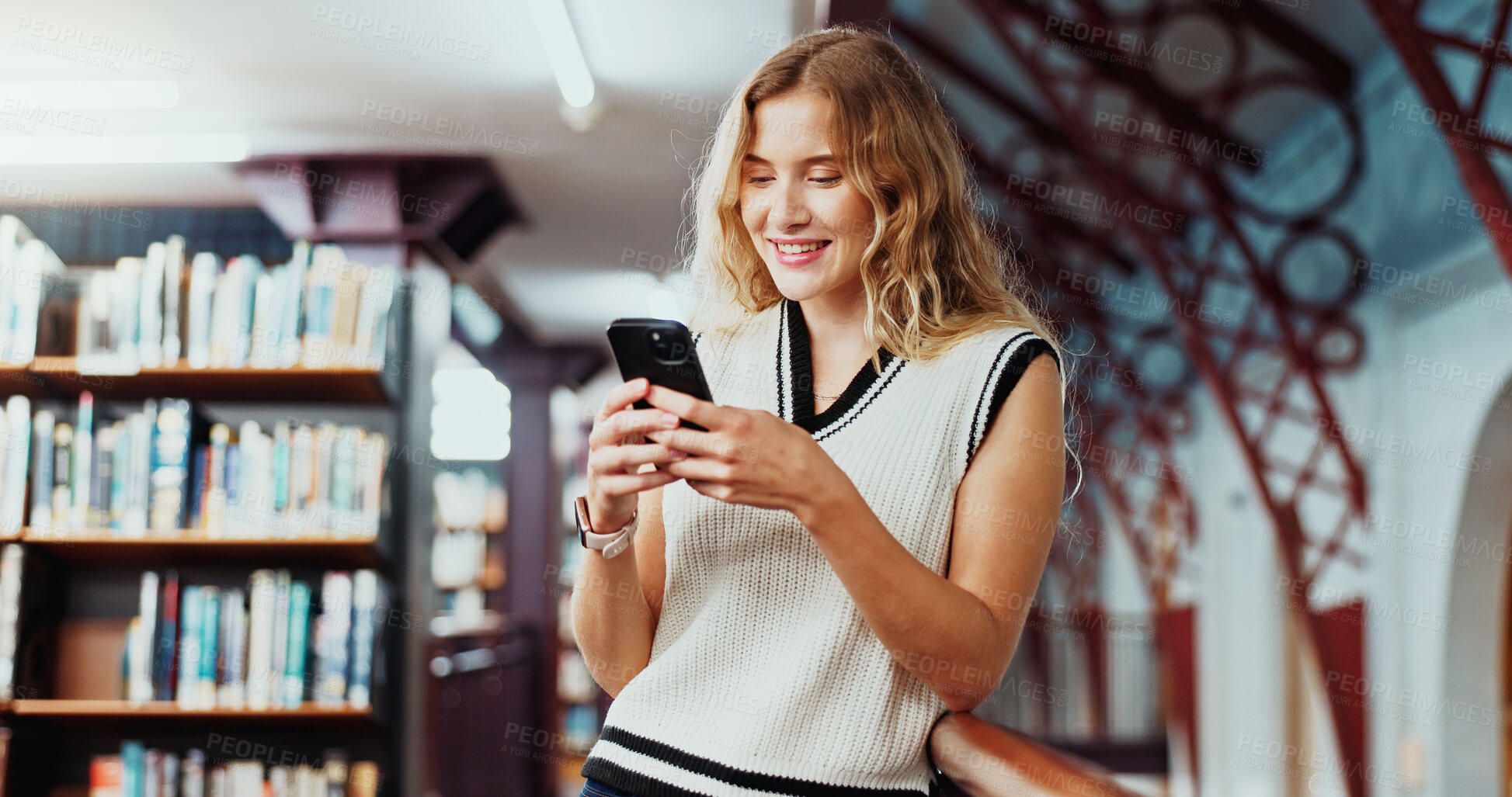 Buy stock photo Girl, college student and texting with phone at library for education, smile or contact at campus. Woman, smartphone and happy for web chat, mobile app and social media on study break at university