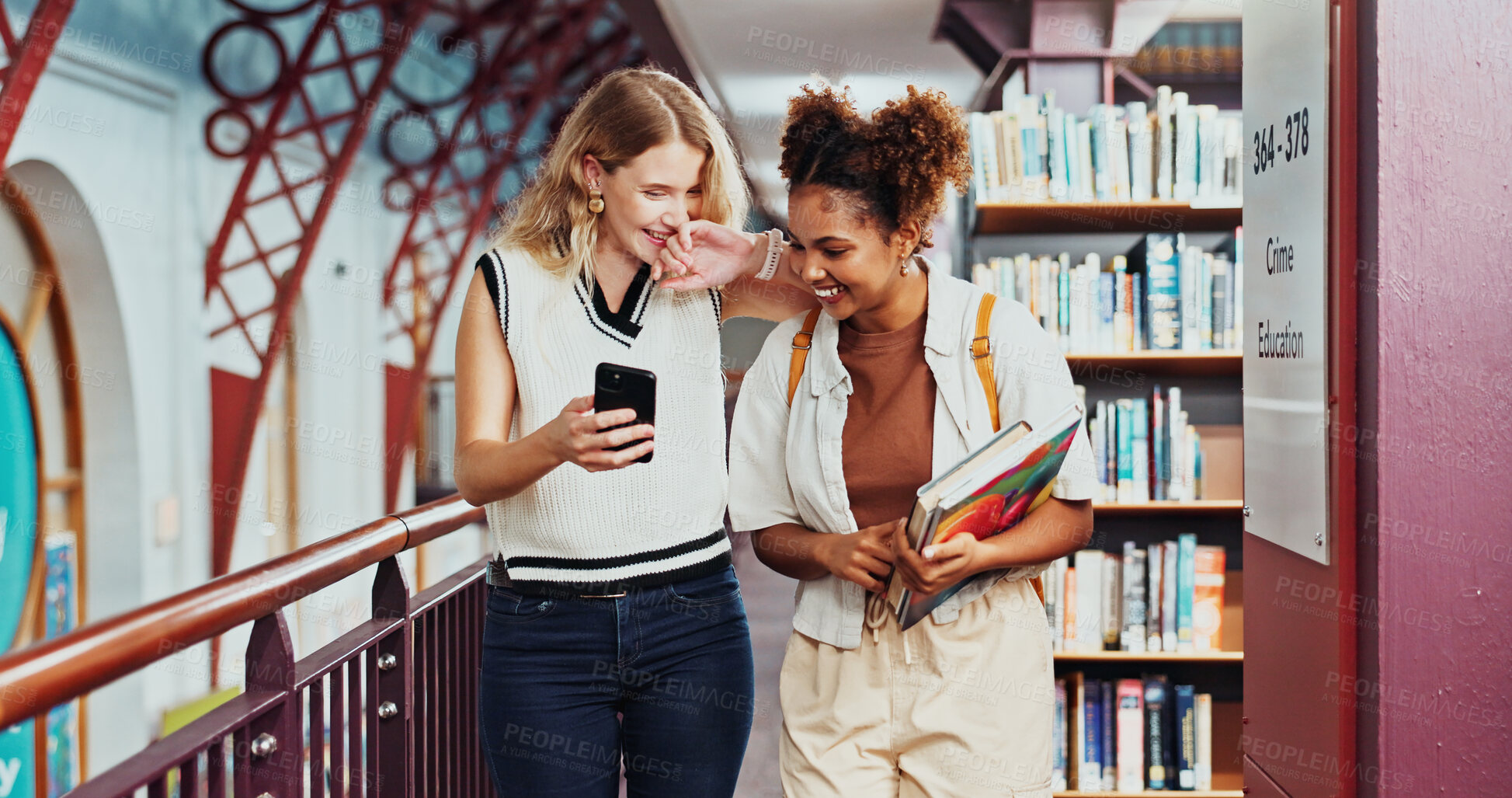 Buy stock photo Laughing, friends and women with smartphone, library or gossip on social media, education and online. University, students and people with mobile for funny post, together and happiness with books