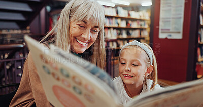 Buy stock photo Grandma, reading book and girl in library, smile and storytelling for child development. Senior woman, kid or family with happiness, teaching or support for education, hobby and literacy with fantasy
