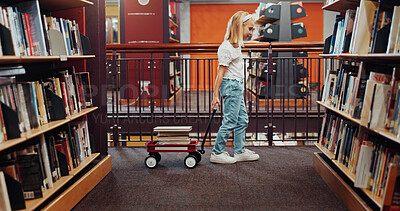 Buy stock photo Education, trolley and walking with girl in library for child development, literature or reading. Books, learning and study with student in elementary school for future, growth or homework assignment
