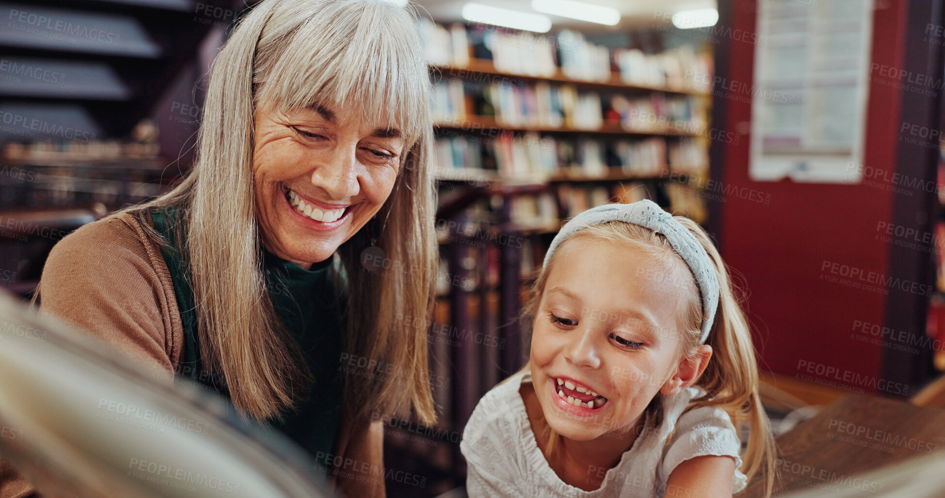 Buy stock photo Grandma, girl and reading book in library with smile, education or knowledge support for development. Family, senior woman and grandchild in bookshop for novel, storytelling or literature for growth.